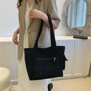 Grand sac cabas en velours côtelé noir avec poche zippée porté par un mannequin