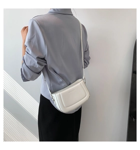 Detail of white PU leather crossbody bag featuring U-shaped quilted stitching and fashion logo