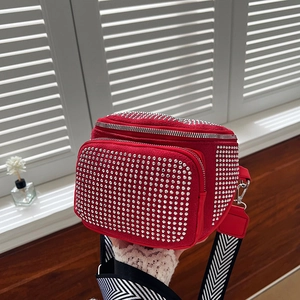 Detail of red rhinestone bucket bag featuring dual zippers and woven chevron strap