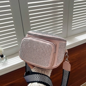Detail of pink rhinestone bucket bag with silver studs and striped woven strap