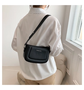 Model view of a black leather underarm bag featuring a silver brand logo on a soft shoulder strap