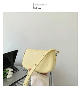 Detail shot of pale yellow leather handbag with white text logo and stylish shoulder strap