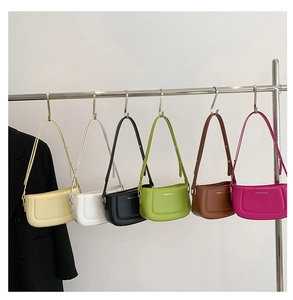 Row of colorful minimalist faux leather shoulder bags displayed on a metal rack