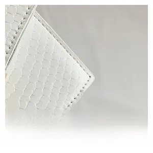 Close-up of white faux crocodile leather texture and precision stitching on the handbag