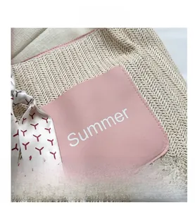 Detail der beigen Stroh-Tasche mit rosa Summer-Patch und dekorativem Seidenschal