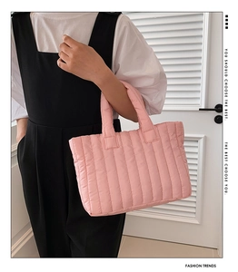 Macro detail of pink quilted nylon tote bag with soft vertical stitching texture