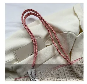 Detail der Strohtasche mit rosa geflochtenem Griff und dekorativem Seidenschal-Akzent