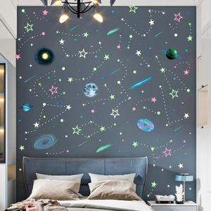 Luminous wall stickers set with stars, moon, and planets on a dark bedroom background