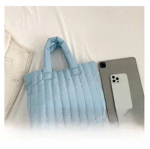 Close-up of light blue quilted puffer tote bag with a soft texture and top handles
