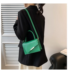 Lifestyle shot of a bright green snake pattern mini crossbody bag with gold hardware