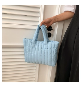 Detail of light blue quilted tote bag made of soft padded fabric for daily use