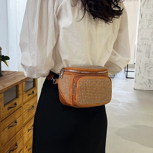 Brown suede bucket bag with rhinestone embellishments worn as a crossbody waist bag