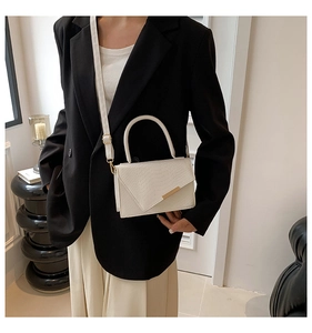 Detail of white crocodile texture crossbody bag with gold metal trim and handle