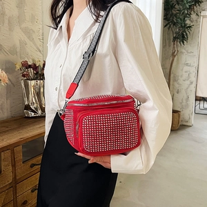 Red rhinestone bucket crossbody bag with striped wide strap worn by a female model