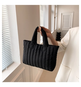 Detail view of a black quilted tote bag with vertical stitching and padded texture design