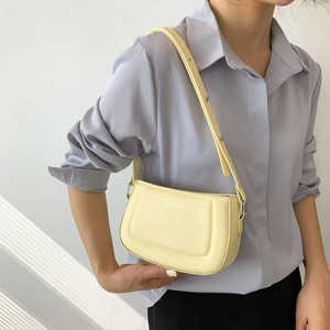 Minimalist light yellow PU leather shoulder bag with silver logo on a female model