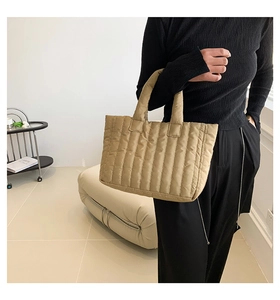 Close-up of khaki quilted puffer tote bag with vertical stripes and padded handle