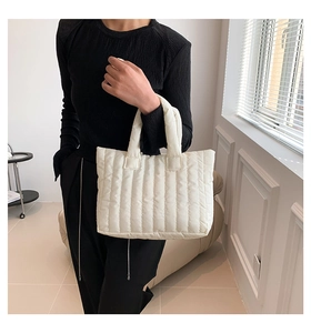 Detail of white quilted tote bag featuring vertical padded texture on soft cotton fabric