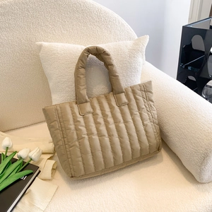 Close-up of a light khaki quilted puffy tote bag on a white fleece sofa in a bright room