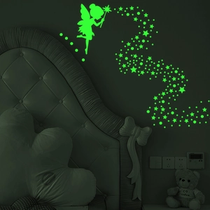 Detailed view of luminous fairy and star wall stickers glowing green in a dark bedroom