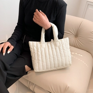 White quilted tote bag with vertical stitching held by model in casual lifestyle setting
