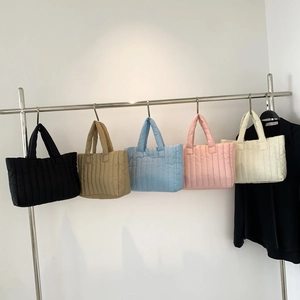 Padded quilted nylon tote bags for women in five assorted colors on a minimalist rack