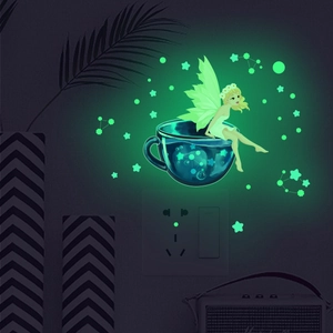 Luminous fairy wall sticker glowing green on wall with stars and teacup design