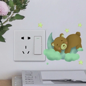 Glow-in-the-dark bear on moon wall sticker shown next to a standard light switch