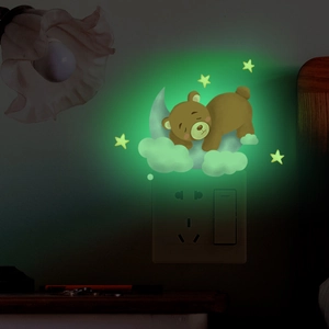 Glow in the dark wall sticker featuring a sleeping bear on a moon with stars near a switch