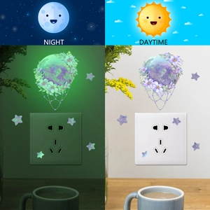 Luminous wall sticker showing glow-in-the-dark moon and flowers in day and night contrast