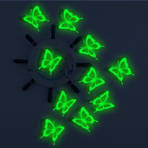 Close-up of 10 glowing 3D hollow butterfly wall stickers in dark green fluorescent light