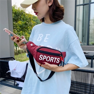 Outdoor shot of a burgundy crossbody sports waist bag with white letter print and adjustable strap