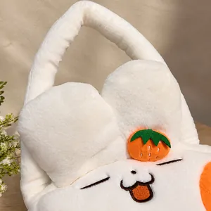 Primer plano del bolso de felpa blanca con bordado de gato y detalle de fruta naranja