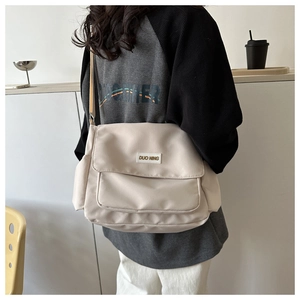 Dettaglio della borsa a tracolla in nylon beige con ampia tasca a patta e placca logo