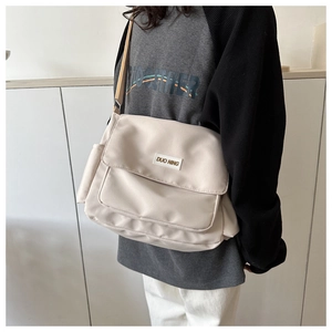 Dettaglio della borsa a tracolla in nylon crema con patta frontale e targa Duo Ning