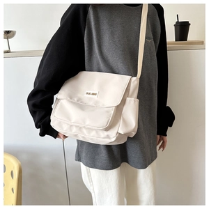 Dettaglio della borsa a tracolla in nylon bianco crema con tasca frontale e tracolla larga