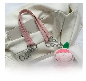Close-up of white leather tote featuring pink strap with silver chain and peach charm