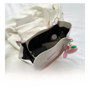 Top view of cream tote bag interior showing large capacity with daily essentials and peach charm