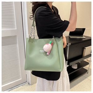 Detail of light green PU tote bag with metal chain strap and peach plush charm