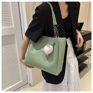Detail of green PU leather tote bag with chain strap and pink peach plush charm
