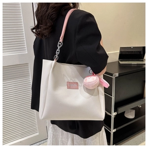 Detail of white PU tote bag with pink leather trim and cute plush doll accessory