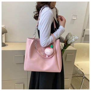 Pink PU leather tote bag featuring a silver chain strap and a peach plush charm detail