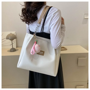 Detail view of large cream tote bag with pink peach charm and metal chain strap