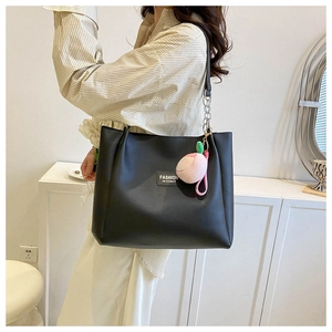 Detailed view of black PU tote bag with silver chain strap and peach plush pendant