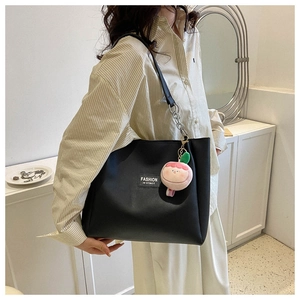 Close-up of black PU tote bag with metal chain strap and a pink peach plush pendant