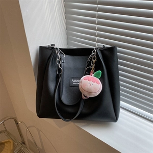 Detail of black PU leather tote bag with silver chain handle and pink peach charm