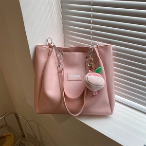 Detail of pink tote bag with silver chain straps and cute peach plush charm accessory