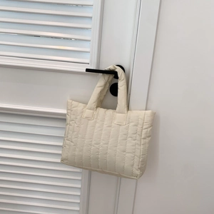 Detail van een crème gewatteerde tote bag aan een vintage deurklink
