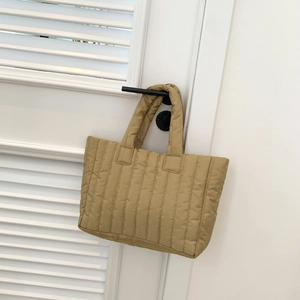 Detail van kaki gewatteerde draagtas hangend aan een witte luikdeur met handvatten