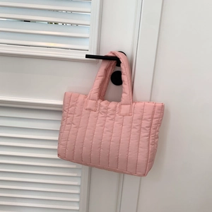 Detailopname van de roze gewatteerde puffer draagtas met verticale strepen aan een deur